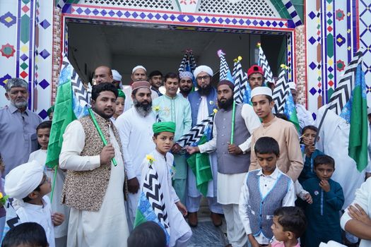 A diverse group of men and boys in traditional attire holding flags at a ceremonial event.
