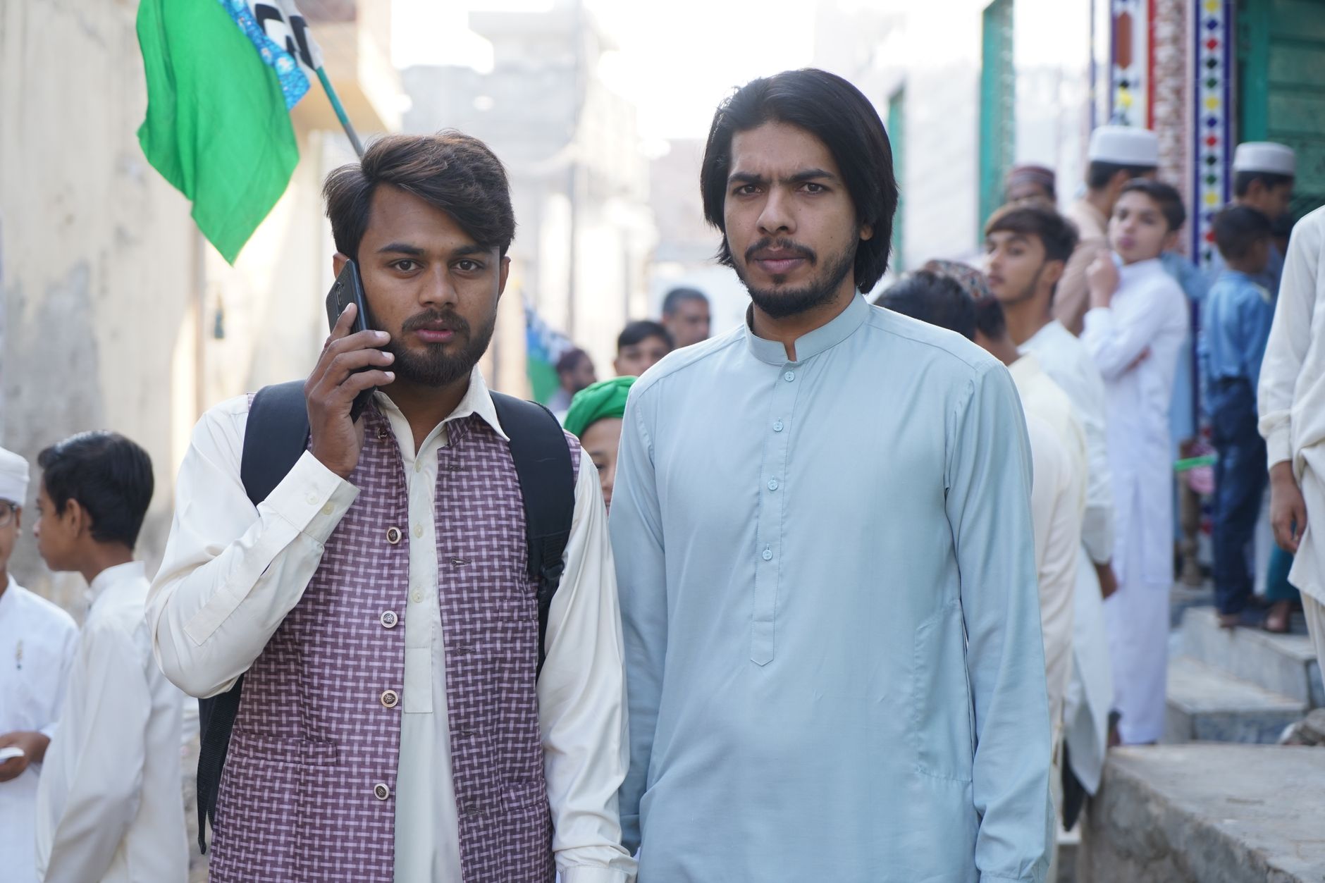 مداح موبائل پر جیو ہاٹ اسٹار کا کرکٹ اسکور دیکھتے ہوئے، پس منظر میں روشن میدان