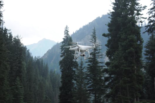 Aerial drone captures breathtaking view in a lush mountain forest, showcasing modern technology and natural beauty.