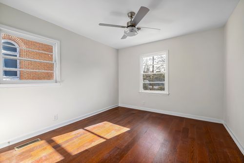 Free Well-lit empty room featuring wooden flooring and a ceiling fan, ideal for apartments or home staging. Stock Photo