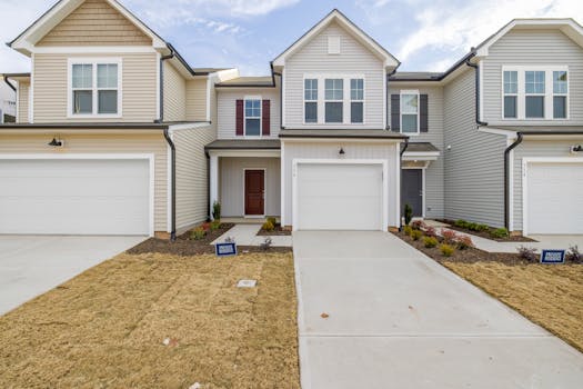 Contemporary suburban homes with garages and neat lawns under a clear sky.