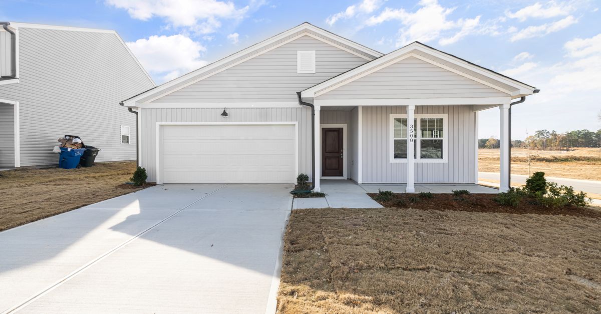 Exterior view of a modern single-story family home with a driveway and front yard.