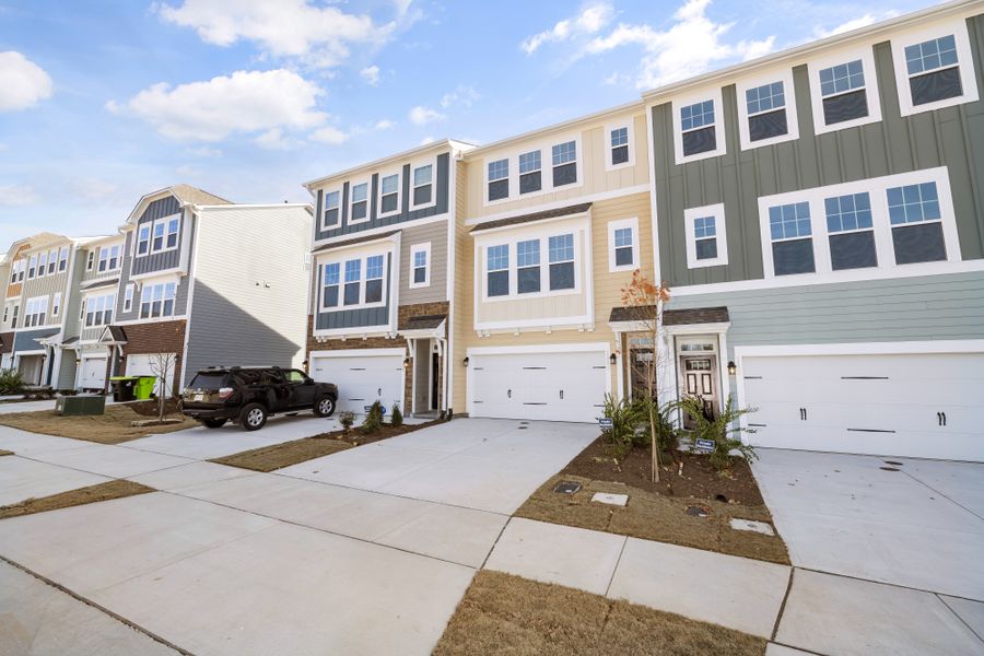 Row of three-storey suburban townhomes with garages and a shared sidewalk