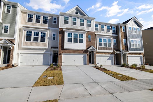 A row of modern suburban townhouses with clean driveways and blue sky backdrop.