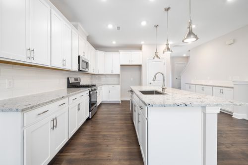 Free Spacious modern kitchen featuring white cabinets, marble countertops, and an island with stainless steel fixtures. Stock Photo