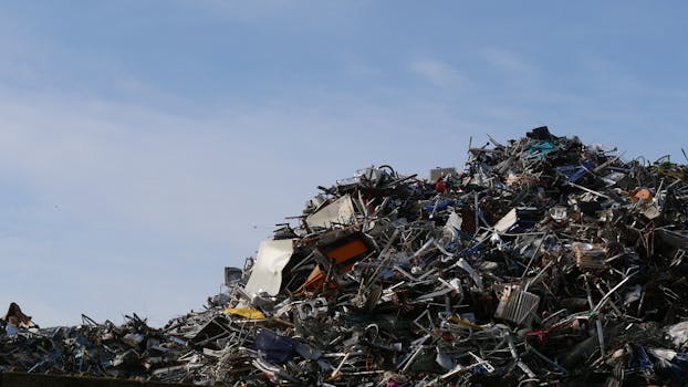 A vast pile of metal scrap and debris under a clear sky, captured at a junkyard.