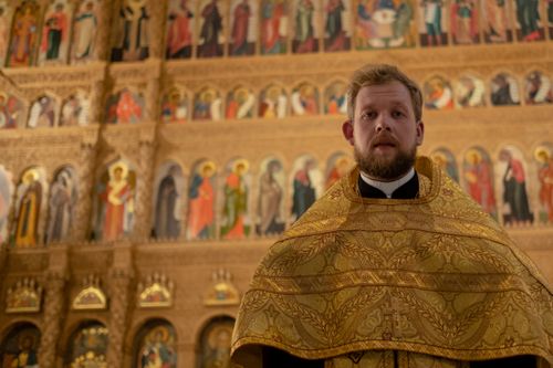 Free A priest stands solemnly in a richly adorned church interior, showcasing religious art. Stock Photo