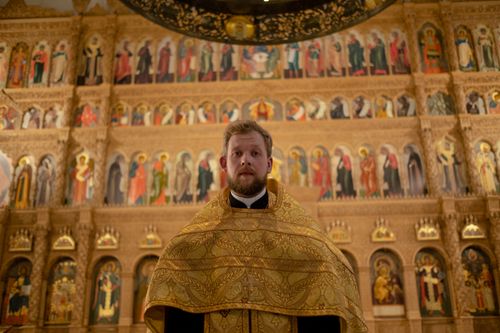 Free Orthodox priest standing before a detailed church iconostasis. Stock Photo