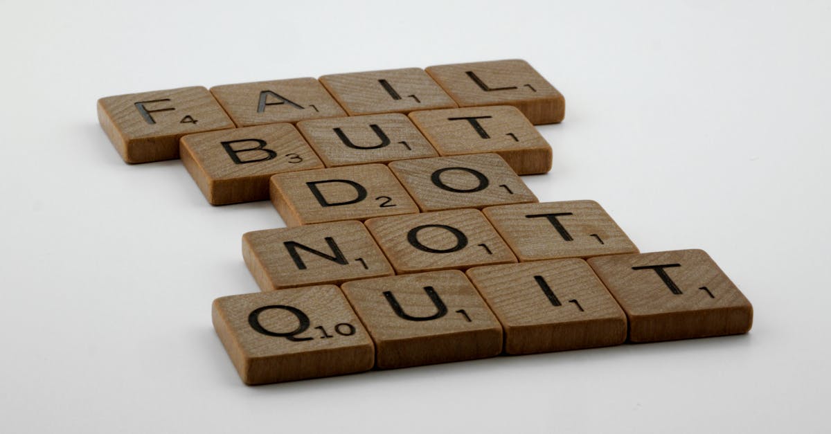 Wooden Scrabble tiles arranged to spell 'Fail but do not quit,' inspiring determination.