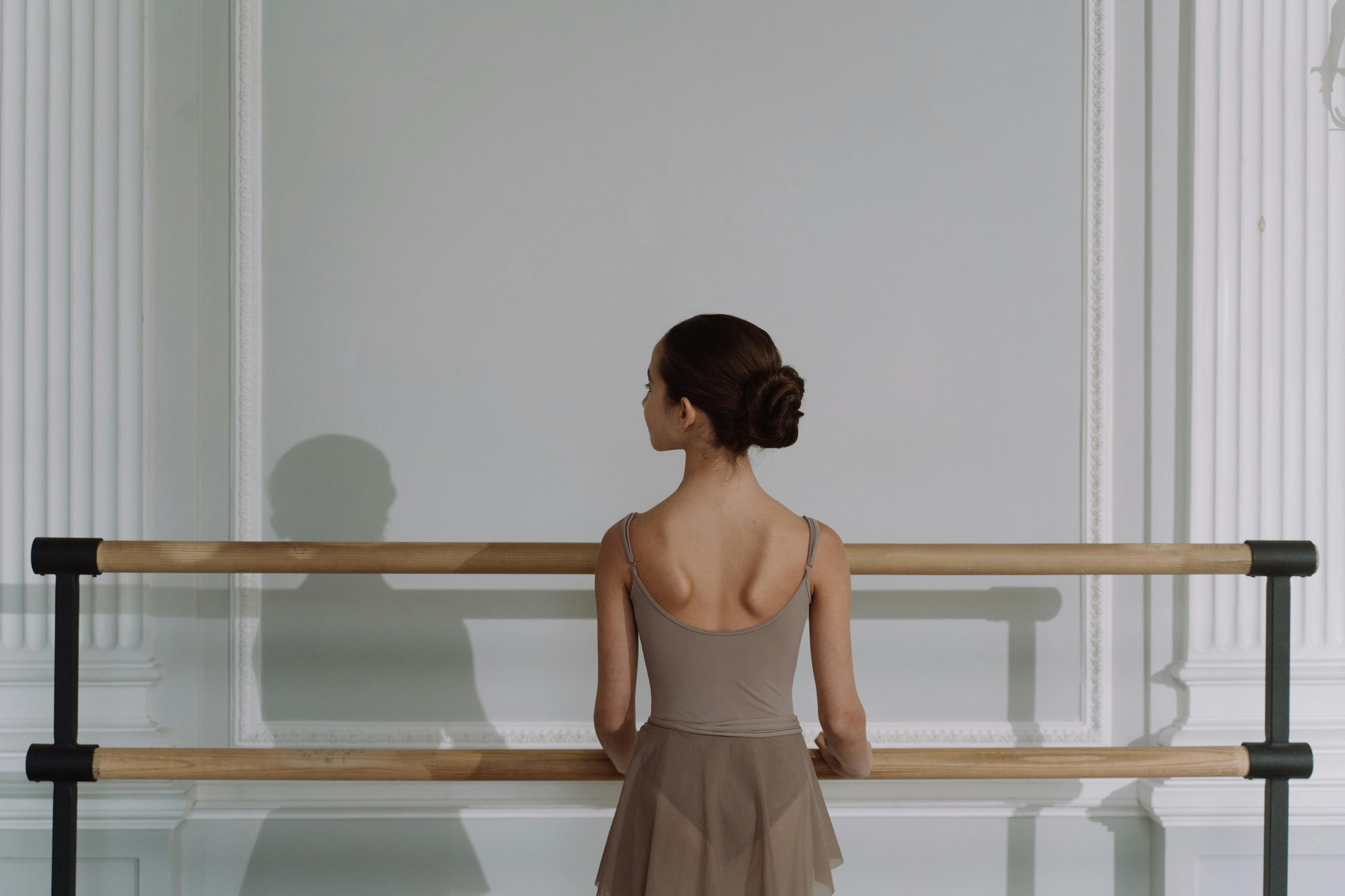 Young ballerina stretching her leg in dance studio. Woman doing