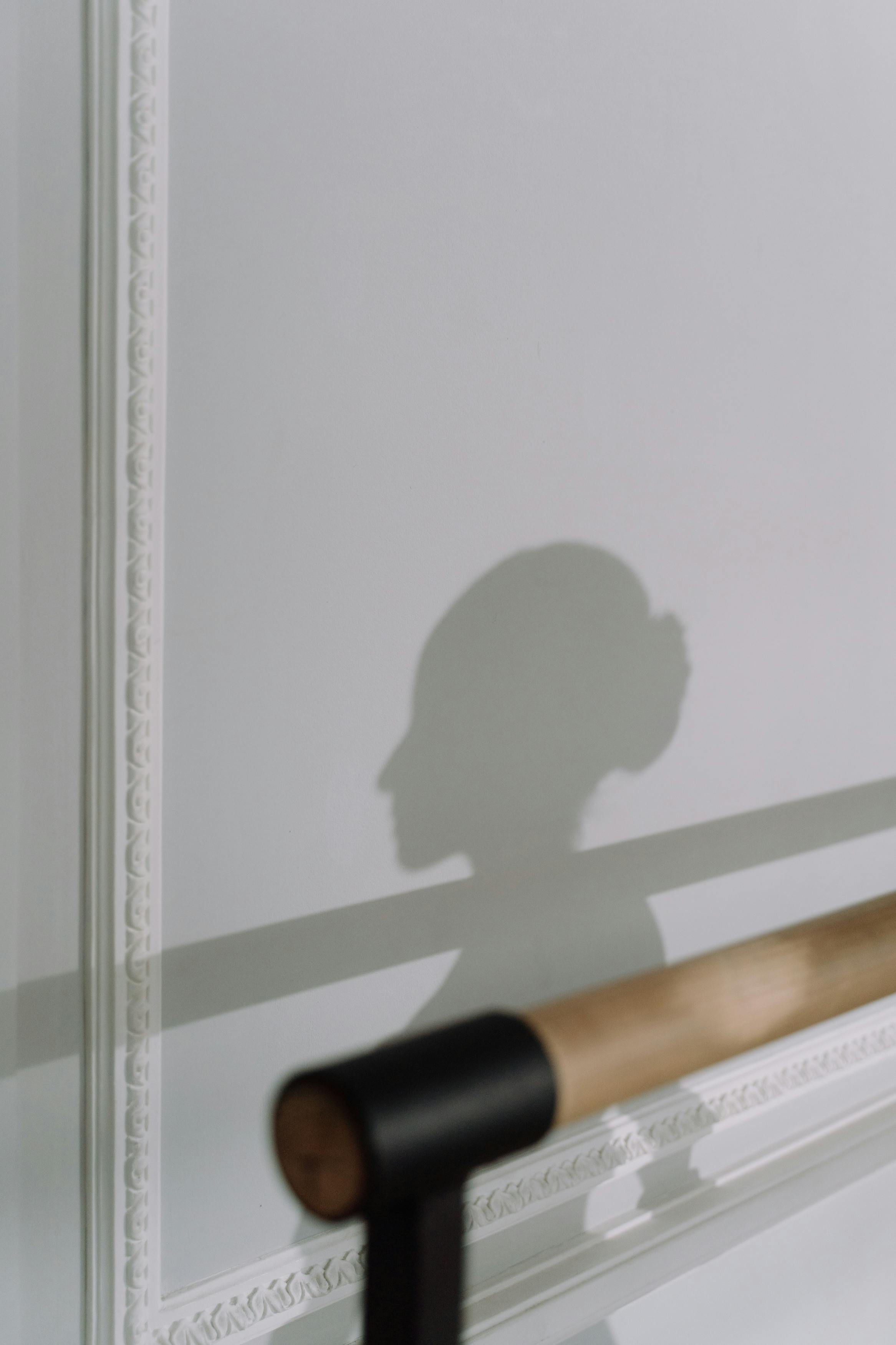 Artistic shadow of a woman's silhouette cast on a white decorative indoor wall.