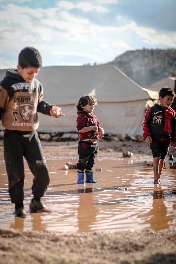 Kids Standing In Dirty Puddle