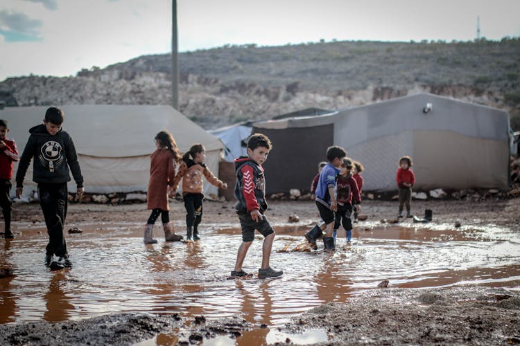 Kids Walking In Mud Against Tents