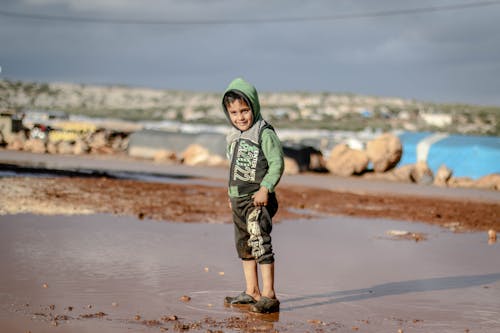 Young Boy standing in a Muddy Puddle 