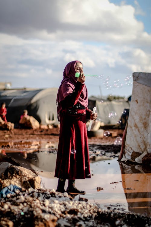 Girl in Red Dress Wearing Hijab Playing with Water Bubbles