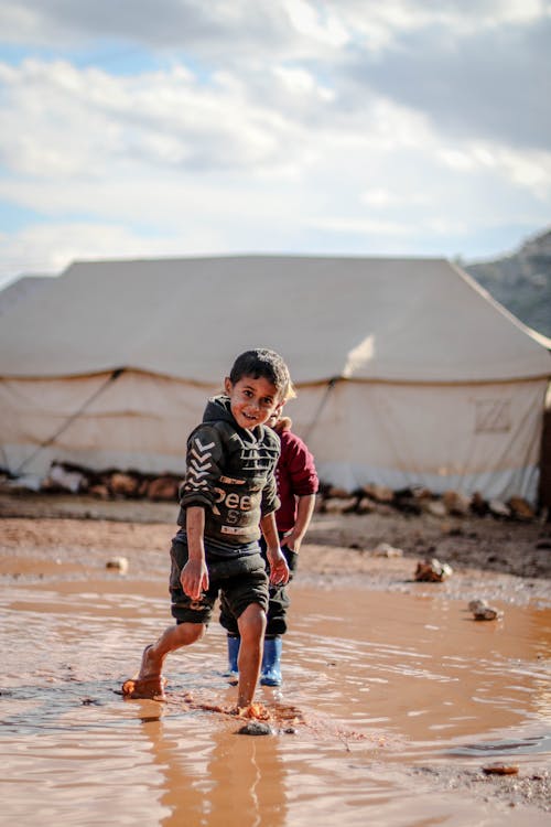 Young Boy walking in a Muddy Puddle