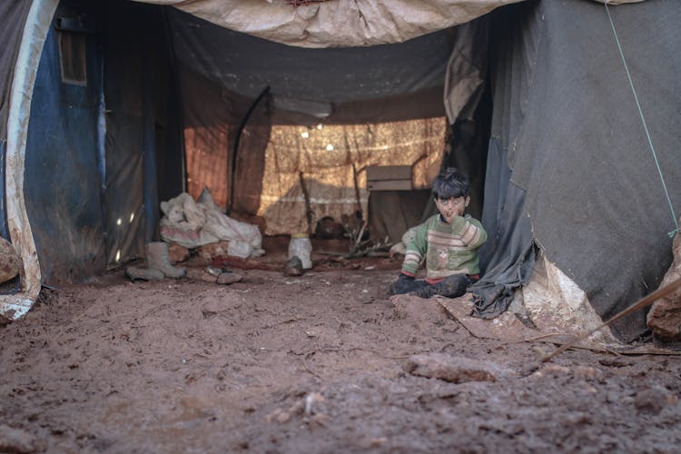 A Boy Sitting On A Muddy Ground 