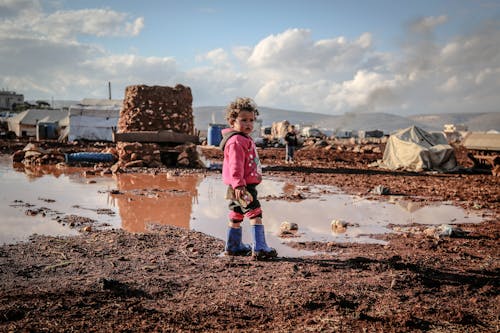 Kid in Sweatshirt Standing on Mud