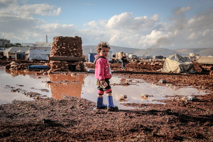 Kid In Sweatshirt Standing On Mud