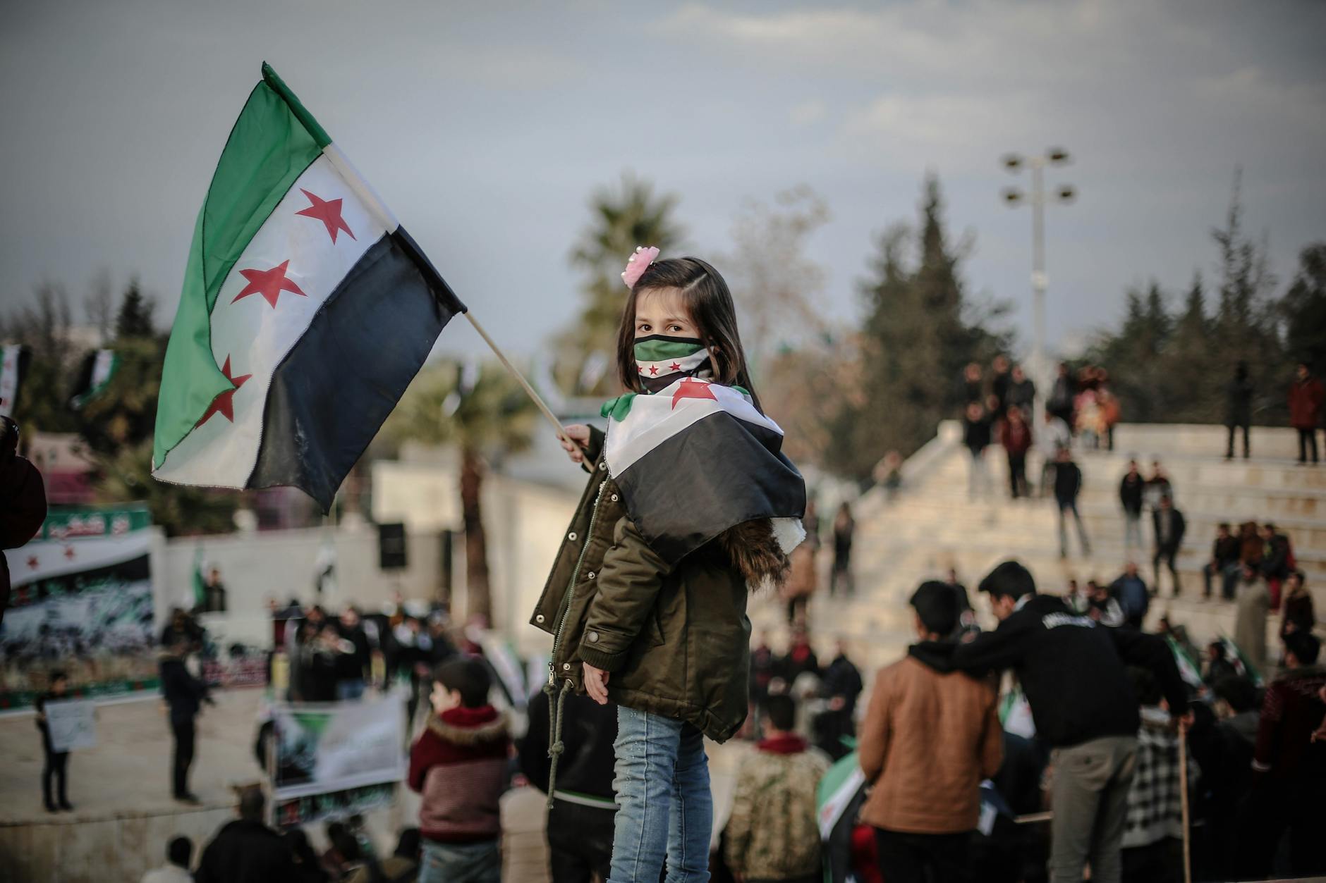 a young girl holding a Syrian flag