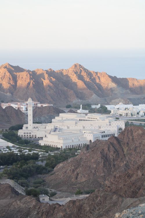Free Aerial view of the Grand Mosque in Muscat, Oman, surrounded by rugged mountains. Stock Photo
