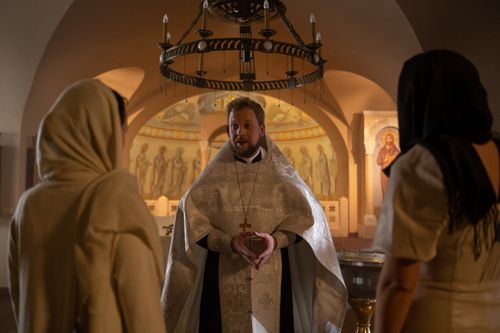 Free A priest delivers a sermon inside a traditional church with two parishioners listening attentively. Stock Photo