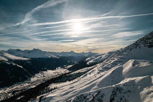 Scenic aerial view of snow-covered peaks in Klosters, Switzerland, under bright sunlight.