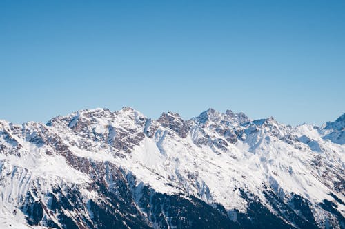 Snow Covered Rocky Mountains Under Clear Blue Sky
