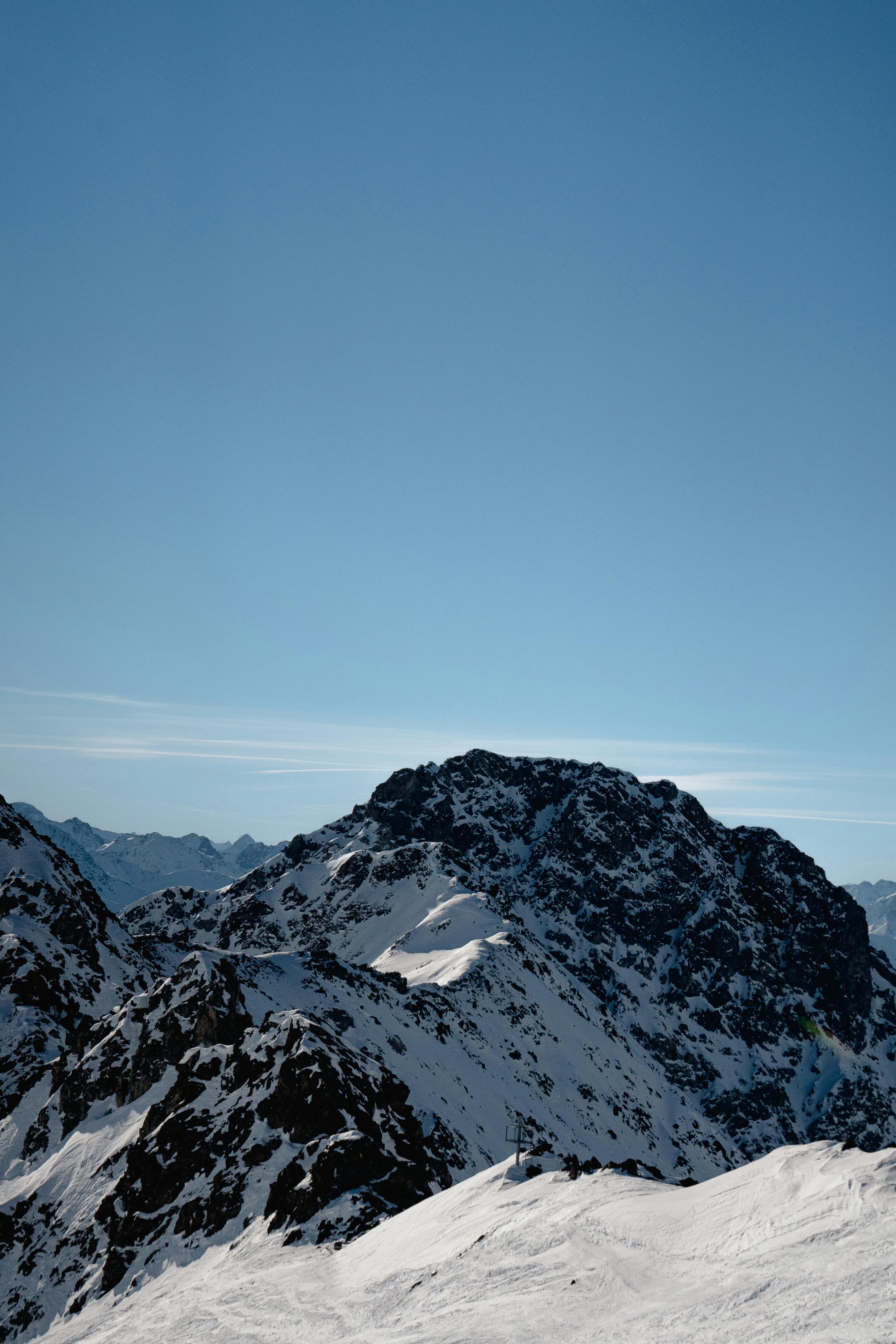 Breathtaking view of snow-covered mountains under a clear blue sky in Klosters-Serneus, Switzerland.