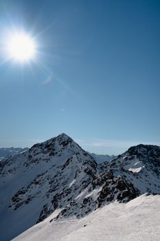 Breathtaking winter view of snow-covered Alps under bright sunlight in Klosters, Switzerland.