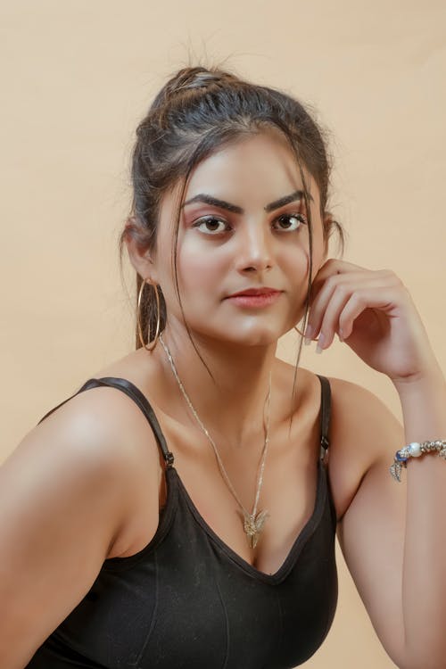 Woman in Black Tank Top with Hand on Cheek
