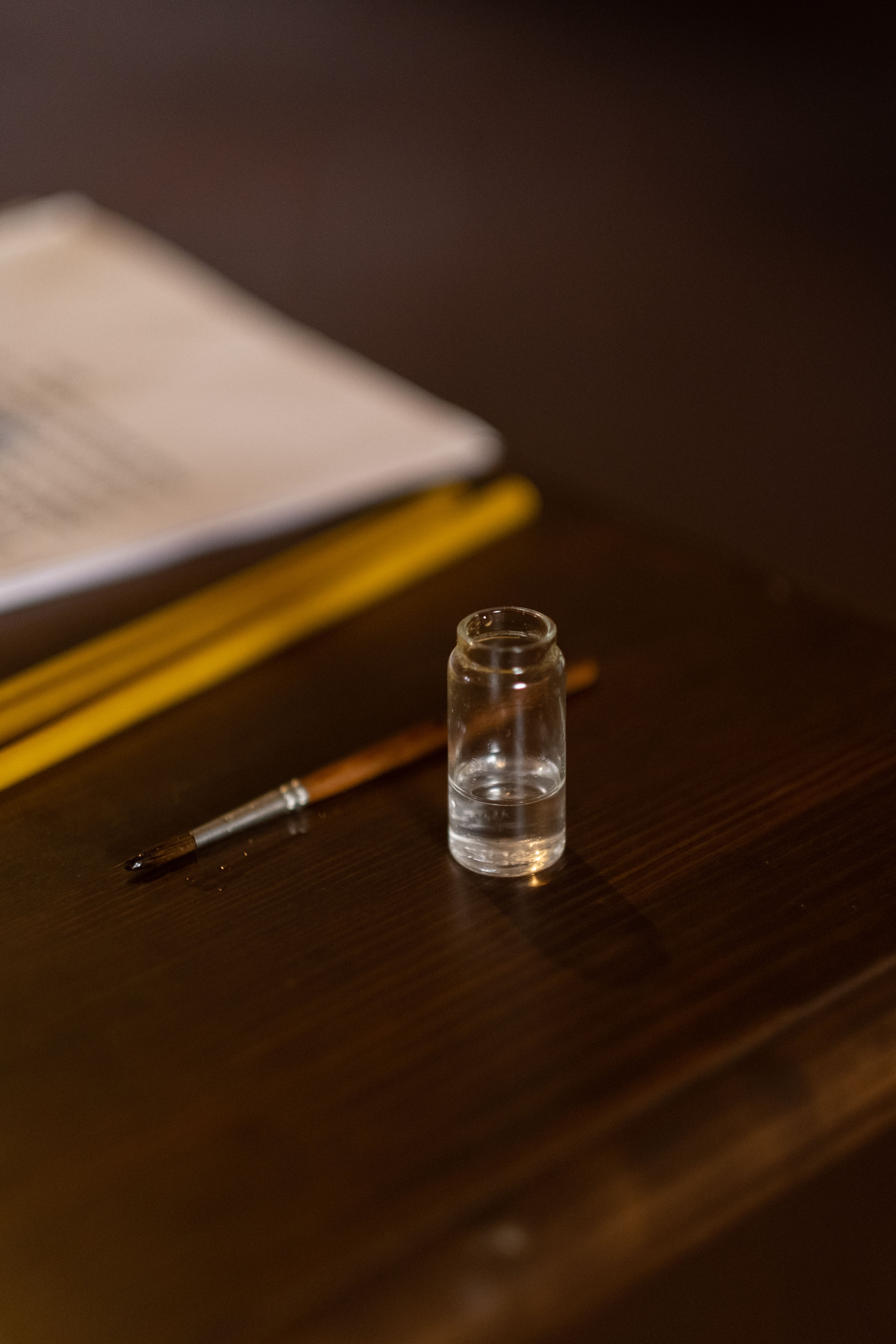A glass jar of holy water beside candles in a quiet church setting