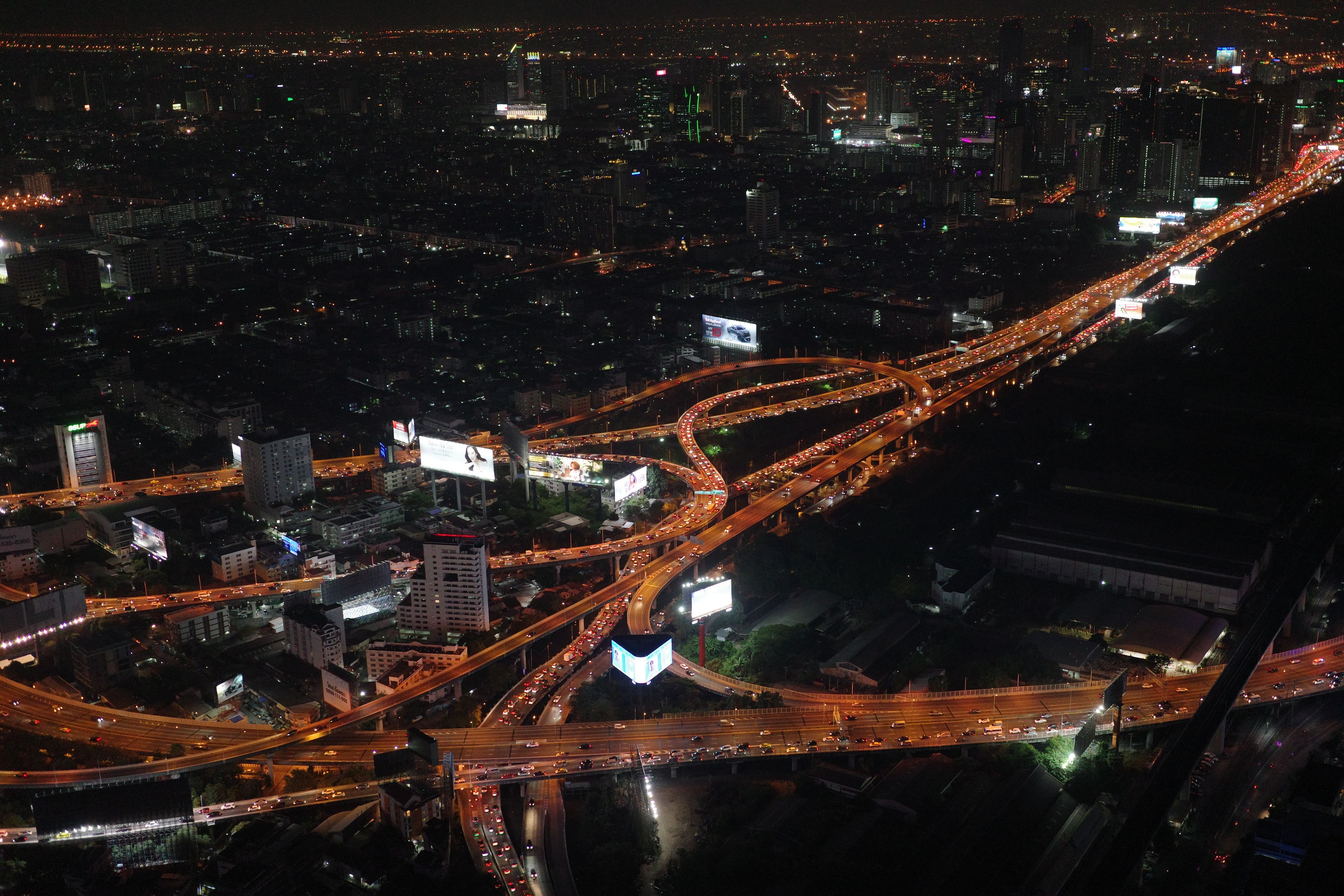 A stunning aerial view of Bangkok's illuminated expressways at night.