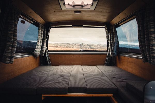 Campervan interior with a made bed facing the mountains