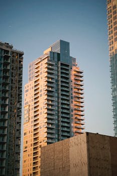 Elevated cityscape view showcasing a modern high-rise building bathed in sunset light.