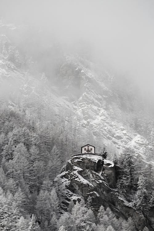 A Grayscale of a House on Top of a Rocky Maountain