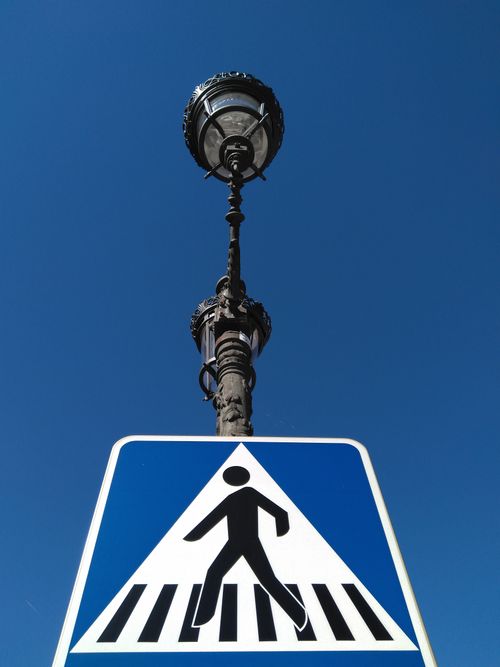 Free A low angle shot of a pedestrian crossing sign with a vintage street lamp against a clear blue sky. Stock Photo
