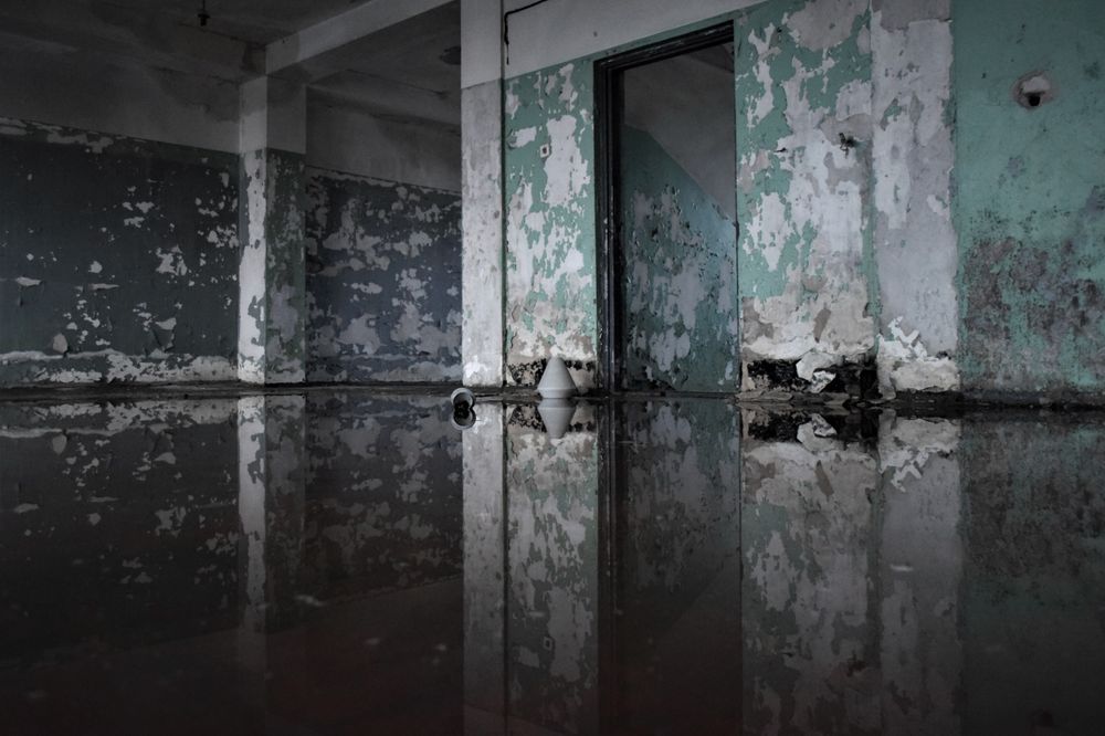 Deteriorated interior with peeling walls and water on the floor — before water damage repair begins