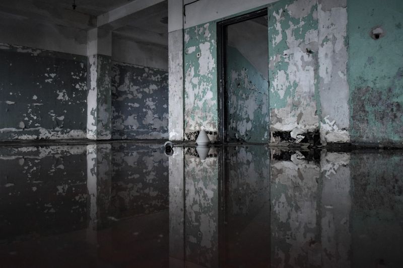 Water-damaged room with flooded floor and peeling paint — what unaddressed basement water intrusion can lead to