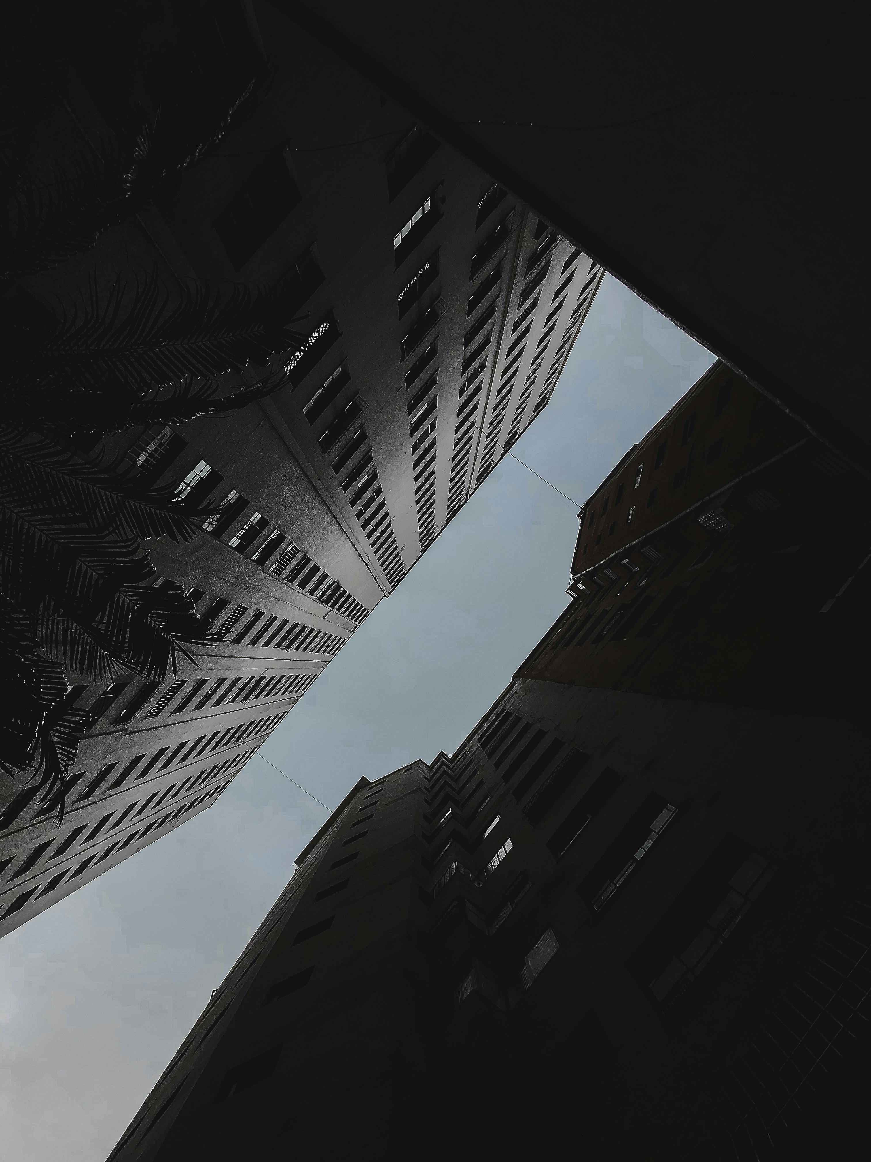 A striking low-angle shot of tall urban buildings converging towards the sky, creating a dynamic architectural perspective.