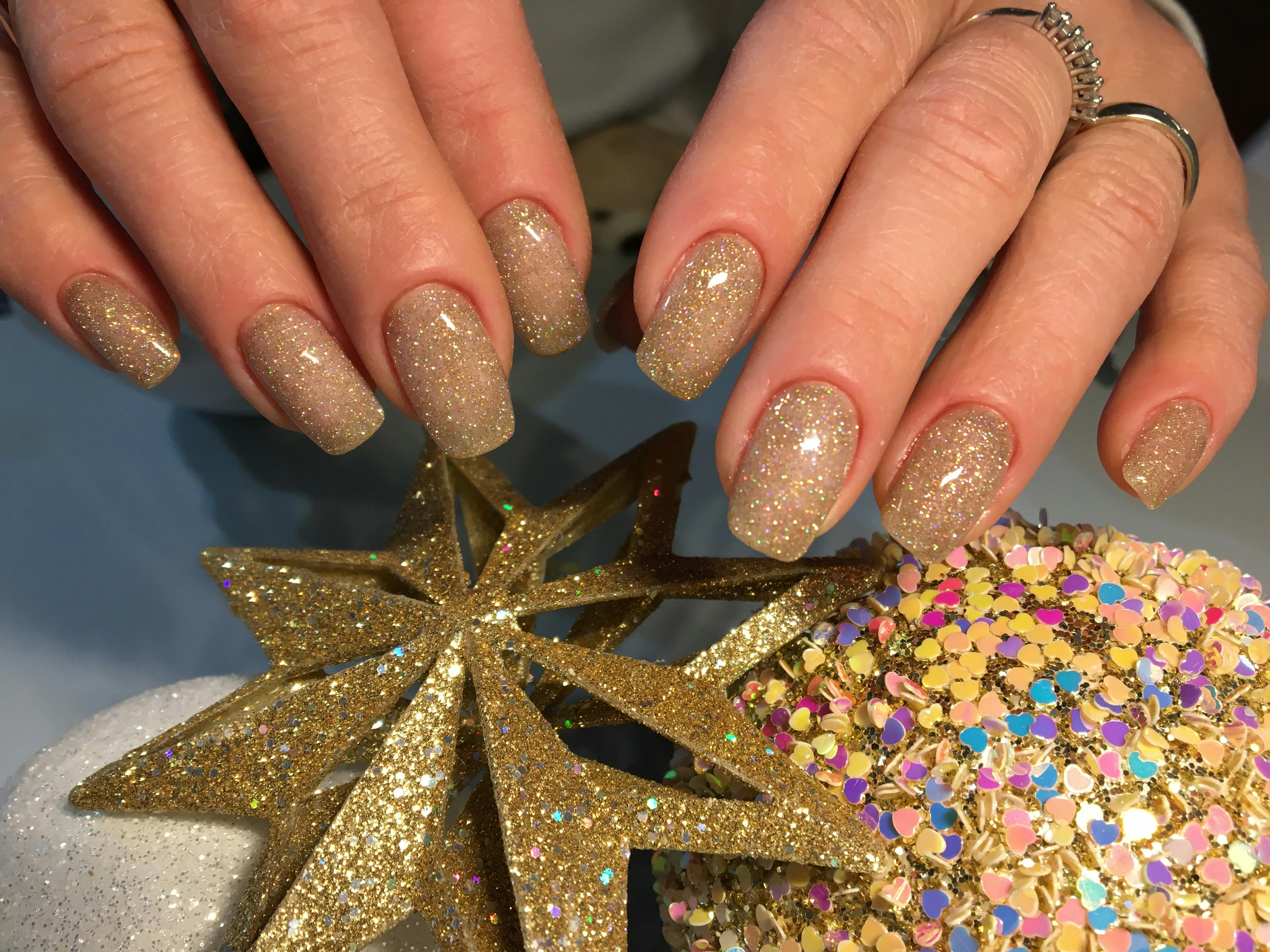 person s hands with gold glitter nails