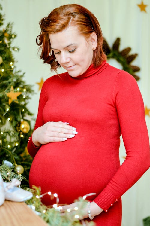 Free Woman in Red Long Sleeve Dress Holding Baby Bump Stock Photo