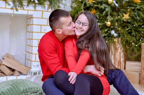 A Man in Red Long Sleeve Shirt Kissing a Woman in Same Shirt
