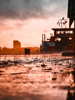 A moody and atmospheric shot of boats in the Hamburg harbor during a rain shower at sunset.