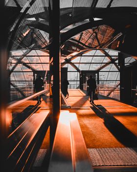 Glass pedestrian bridge in Hamburg with silhouetted figures and reflections.