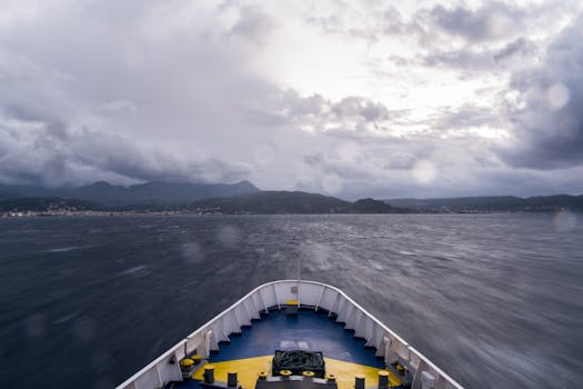 View from a boat navigating rough seas towards mountainous coastline under a cloudy sky.