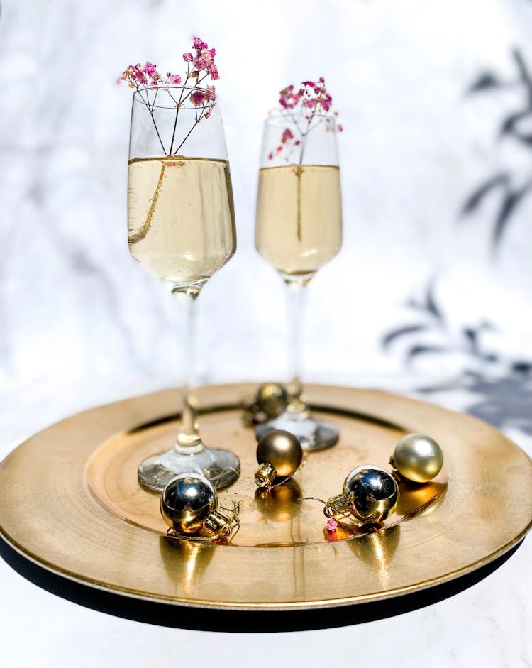 Two Champagne Glasses On Golden Round Plate Beside Christmas Balls 