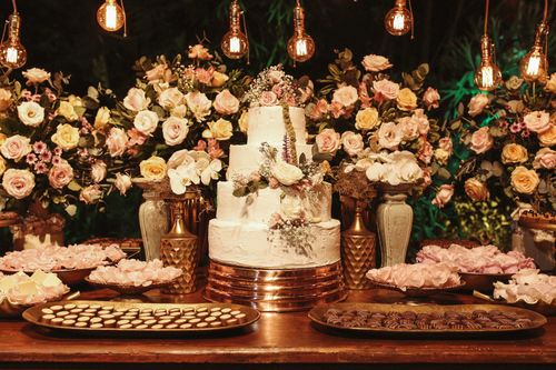 Free A beautifully decorated wedding cake with flower arrangements and assorted desserts, creating a romantic celebration setting. Stock Photo