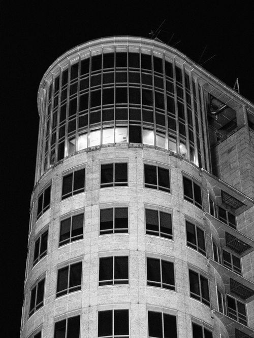Free A striking black and white image of a modern highrise building at night, highlighting its architectural design. Stock Photo