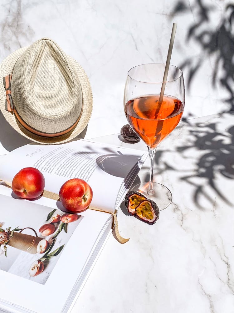 Still Life With Cocktail, Fedora Hat, Open Book And Fruits